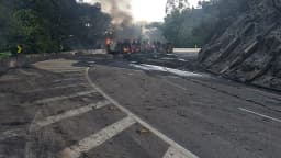 Imagem de arquivo mostra veículos em chamas interditando pista da BR-040 após outro acidente, com fumaça densa subindo entre a vegetação