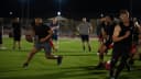 Jogadores disputam partida de flag football em campo iluminado (imagem de arquivo, não é da seleção brasileira)