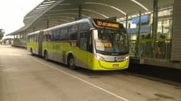 Ônibus articulado verde do sistema MOVE parado em estação do transporte coletivo de Belo Horizonte, com passageiros aguardando na plataforma