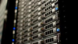 Fileira de servidores em rack de data center, luzes azuis indicando atividade, foto ilustrativa de infraestrutura de computação