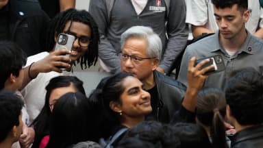 Jensen Huang, CEO da Nvidia, cercado por estudantes que tiram fotos com ele após palestra em Stanford