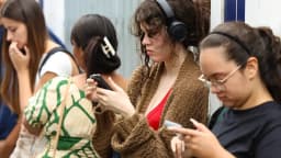 Jovens usam celular enquanto aguardam em fila (foto de arquivo, sobre formalização do trabalho entre jovens)