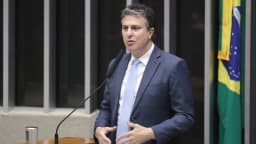 O senador Camilo Santana discursa em evento oficial com a bandeira do Brasil ao fundo
