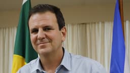 Eduardo Paes, prefeito do Rio de Janeiro, posa com as bandeiras do Brasil e da cidade ao fundo