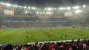 Torcida acompanha jogo do Flamengo no Maracanã, com o gramado iluminado ao fundo