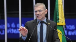 Senador Fabiano Contarato discursa em tribuna com a bandeira do Brasil ao fundo