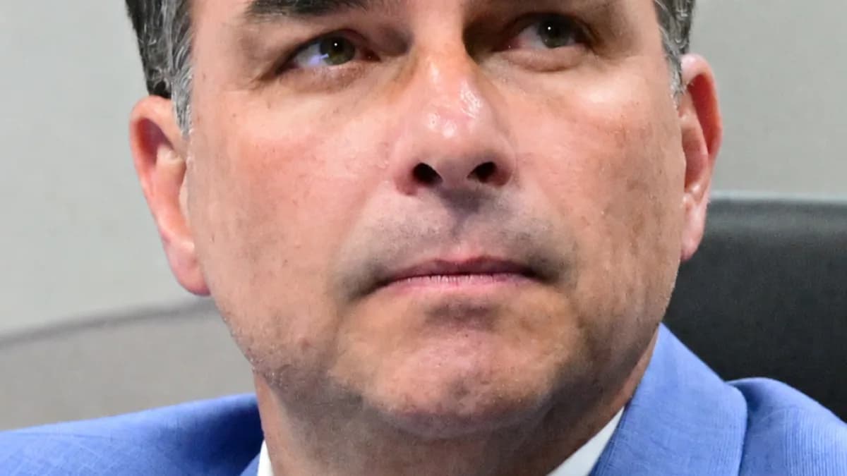 Flávio Bolsonaro de terno azul, olhando para cima, em sessão de comissão no Senado