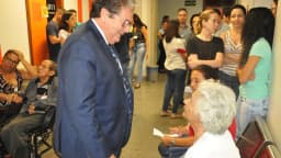 Idosos em ambiente de convivência conversando com profissional de saúde em corredor de hospital