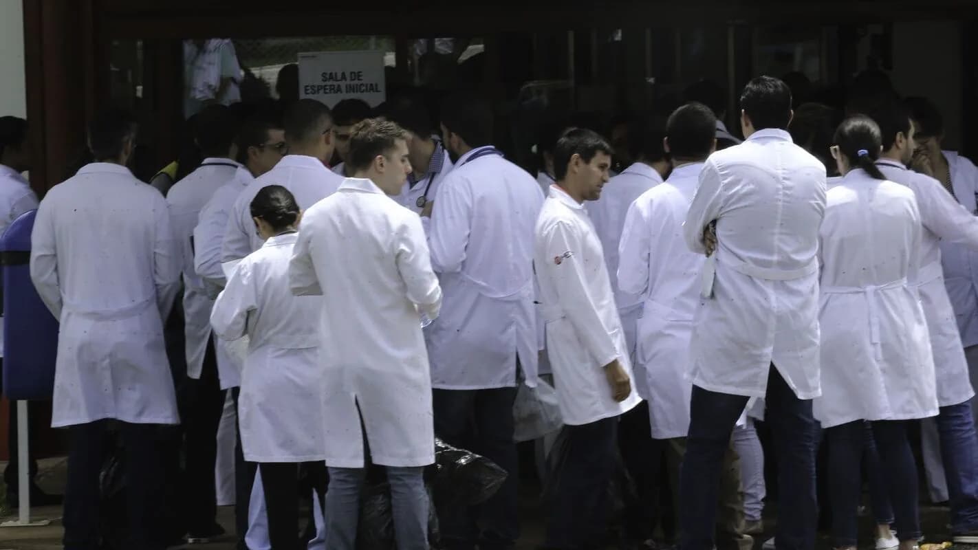 Grupo de médicos de jaleco branco reunidos na entrada de um centro de provas, foto de arquivo