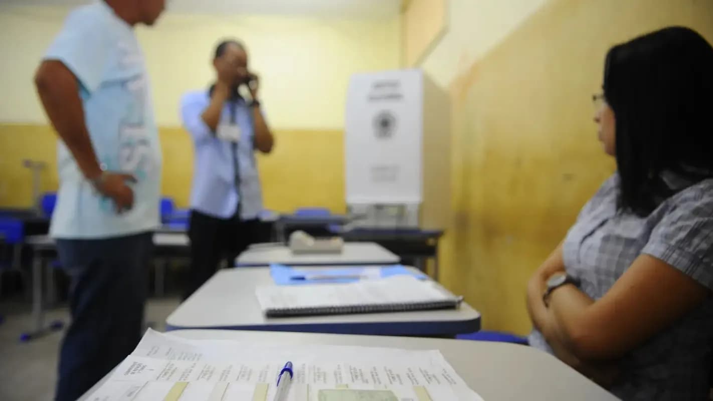 Mesário auxilia eleitora durante votação em urna eletrônica