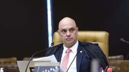 Ministro Alexandre de Moraes, de toga, sentado na bancada do plenário do STF durante sessão, com microfone e documentos à frente
