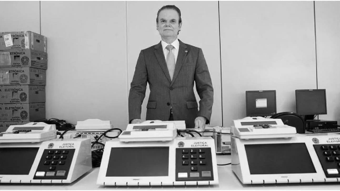 Urna eletrônica brasileira com técnico do TSE ao fundo