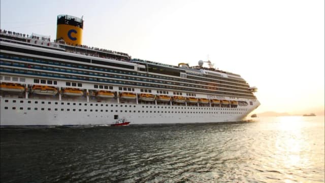 Navio de cruzeiro Costa Serena ao entardecer no porto de Santos, com passageiros no convés