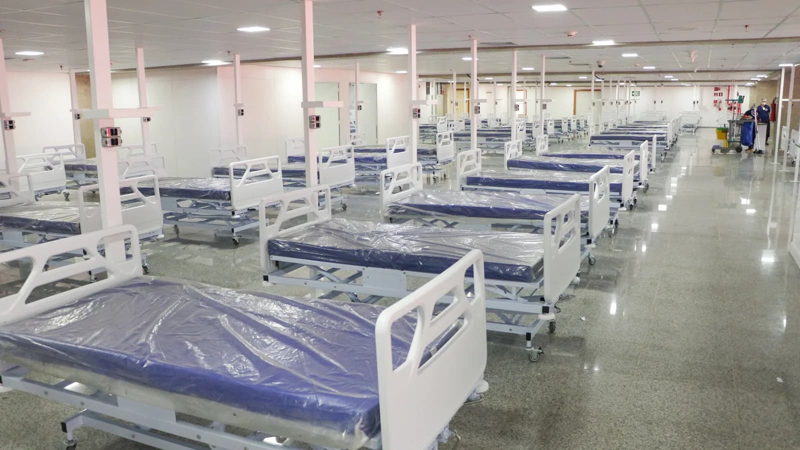Fileira de leitos hospitalares vazios em sala ampla de hospital de campanha