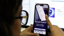 Pessoa consulta o aplicativo da Receita Federal no celular para verificar restituição do Imposto de Renda