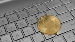 Moeda física de bitcoin sobre teclado de notebook, foto ilustrativa