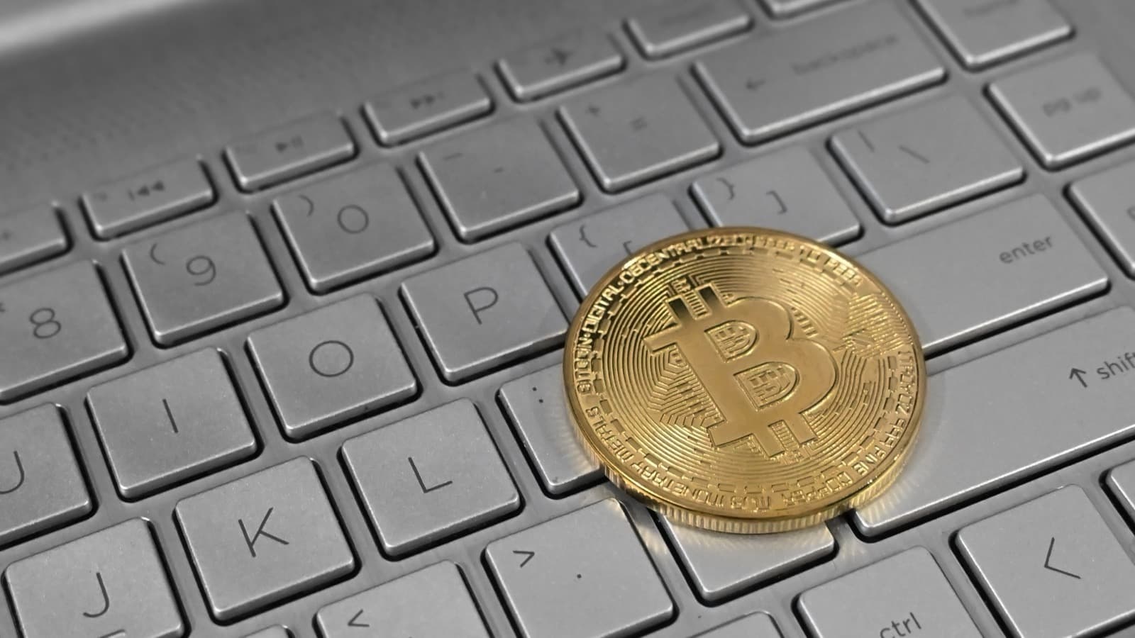 Moeda física de bitcoin sobre teclado de notebook, foto ilustrativa