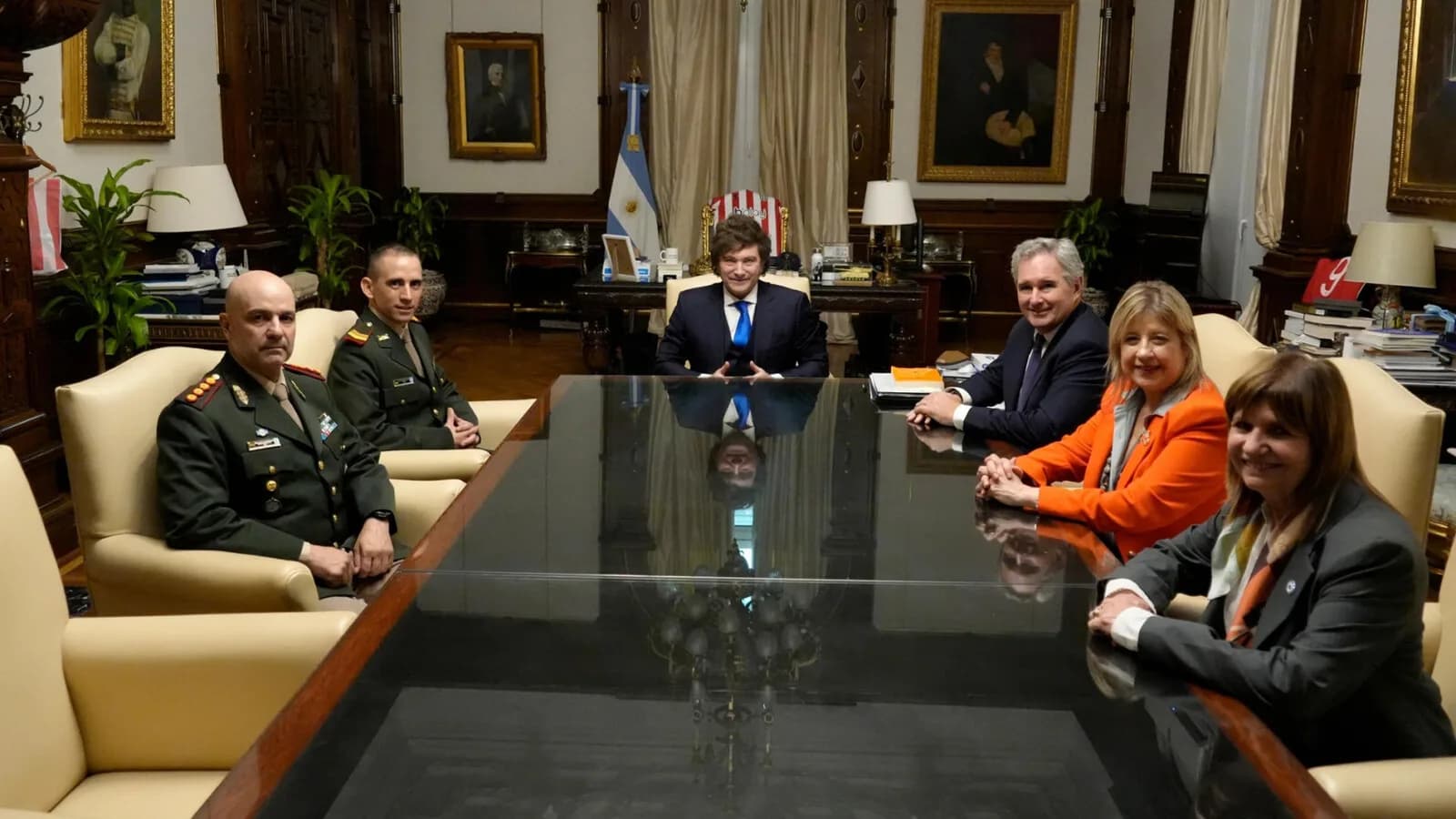 Javier Milei reunido com integrantes do governo argentino em sala com bandeira da Argentina