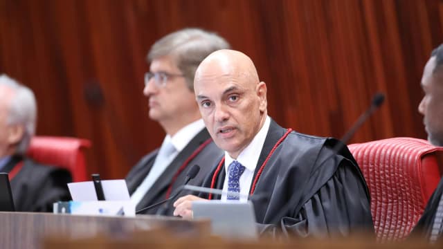 O ministro Alexandre de Moraes fala ao microfone durante sessão de julgamento, vestindo toga
