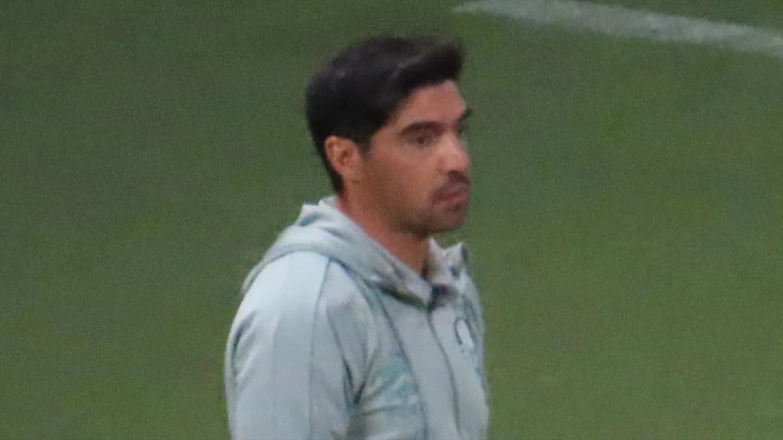 Técnico Abel Ferreira observa o jogo à beira do gramado, com o escudo do Palmeiras no agasalho