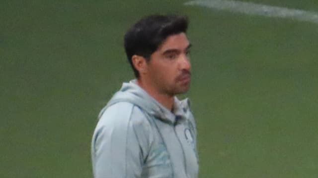 Técnico Abel Ferreira observa o jogo à beira do gramado, com o escudo do Palmeiras no agasalho
