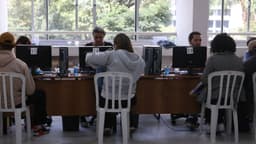 Consumidores sentados de costas são atendidos em guichês numerados com computadores durante mutirão de renegociação de dívidas; imagem de arquivo