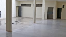 Corredor interno da penitenciária federal de segurança máxima de Brasília, com portas de grade e bancos de concreto
