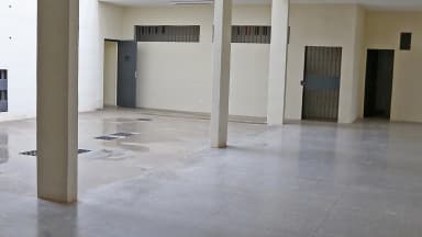 Corredor interno da penitenciária federal de segurança máxima de Brasília, com portas de grade e bancos de concreto