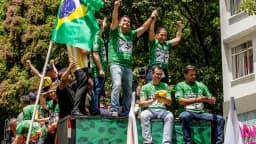 Flávio Bolsonaro levanta o braço ao lado de apoiadores em ato de campanha na Avenida Paulista