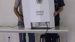 Mesário auxilia eleitor em cabine de votação da Justiça Eleitoral