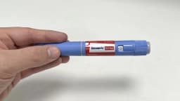 Mão segurando uma caneta injetável de Ozempic (semaglutida), medicamento da classe GLP-1 usado no tratamento de diabetes e obesidade