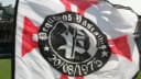 Bandeira da torcida organizada Pequenos Vascaínos tremulando em estádio, com o símbolo do Vasco da Gama ao centro