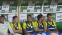 Jefté sentado no banco de reservas do Palmeiras ao lado de outros jogadores, com uniforme reserva amarelo e azul
