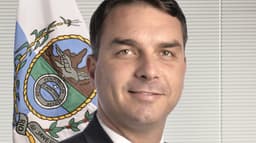 Flávio Bolsonaro, foto oficial de senador, com a bandeira do Rio de Janeiro ao fundo