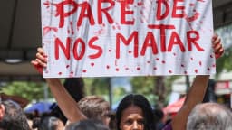 Mulher segura cartaz de protesto contra a violência de gênero em manifestação pública