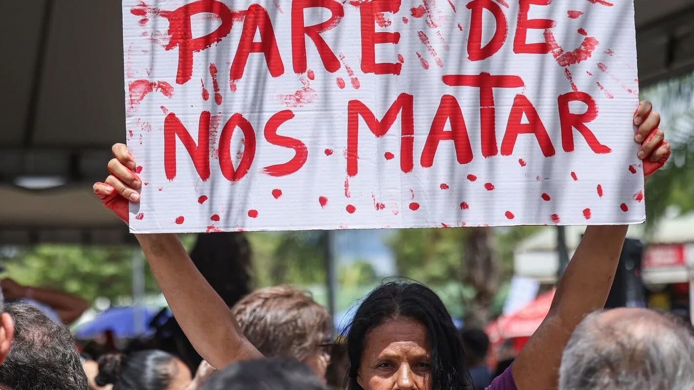 Mulher segura cartaz de protesto contra a violência de gênero em manifestação pública