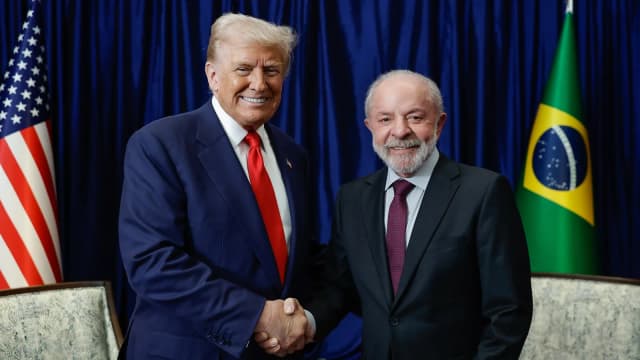 Lula e Donald Trump se cumprimentam durante encontro bilateral, com bandeiras do Brasil e dos Estados Unidos ao fundo