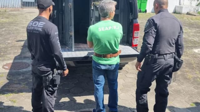 Policiais penais escoltam detento ao lado de viatura durante operação prisional
