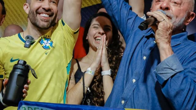 Lula ergue o punho ao lado de bandeira do Brasil em comemoração à reeleição