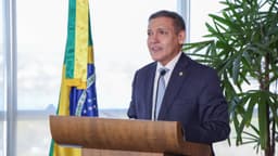 Autoridade discursa em púlpito com a bandeira do Brasil ao fundo, durante evento institucional do TSE sobre o período eleitoral de 2026, em Brasília