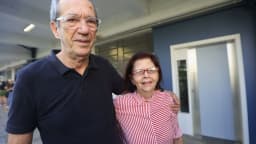 Casal de idosos sorri abraçado em local de votação movimentado em São Paulo