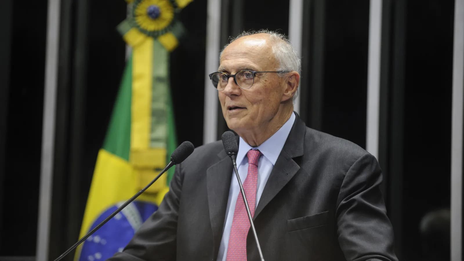 Senador discursa no plenário do Senado Federal, com a bandeira do Brasil ao fundo