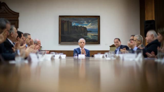 Executivos reunidos em sala de reunião assinando documentos