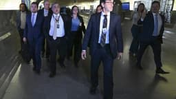 Carlos Roberto Ferreira Lopes, de terno escuro e crachá de identificação, é conduzido por corredor do Congresso Nacional acompanhado de assessores