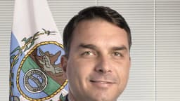 Flávio Bolsonaro (PL-RJ) em foto oficial do Senado, com a bandeira do Rio de Janeiro ao fundo