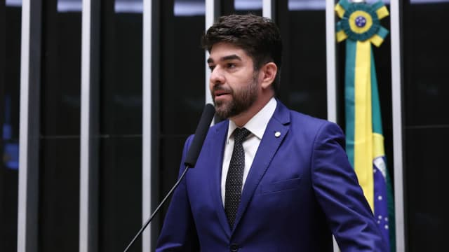 O deputado federal Zé Vitor discursa ao microfone no plenário da Câmara dos Deputados, de terno azul