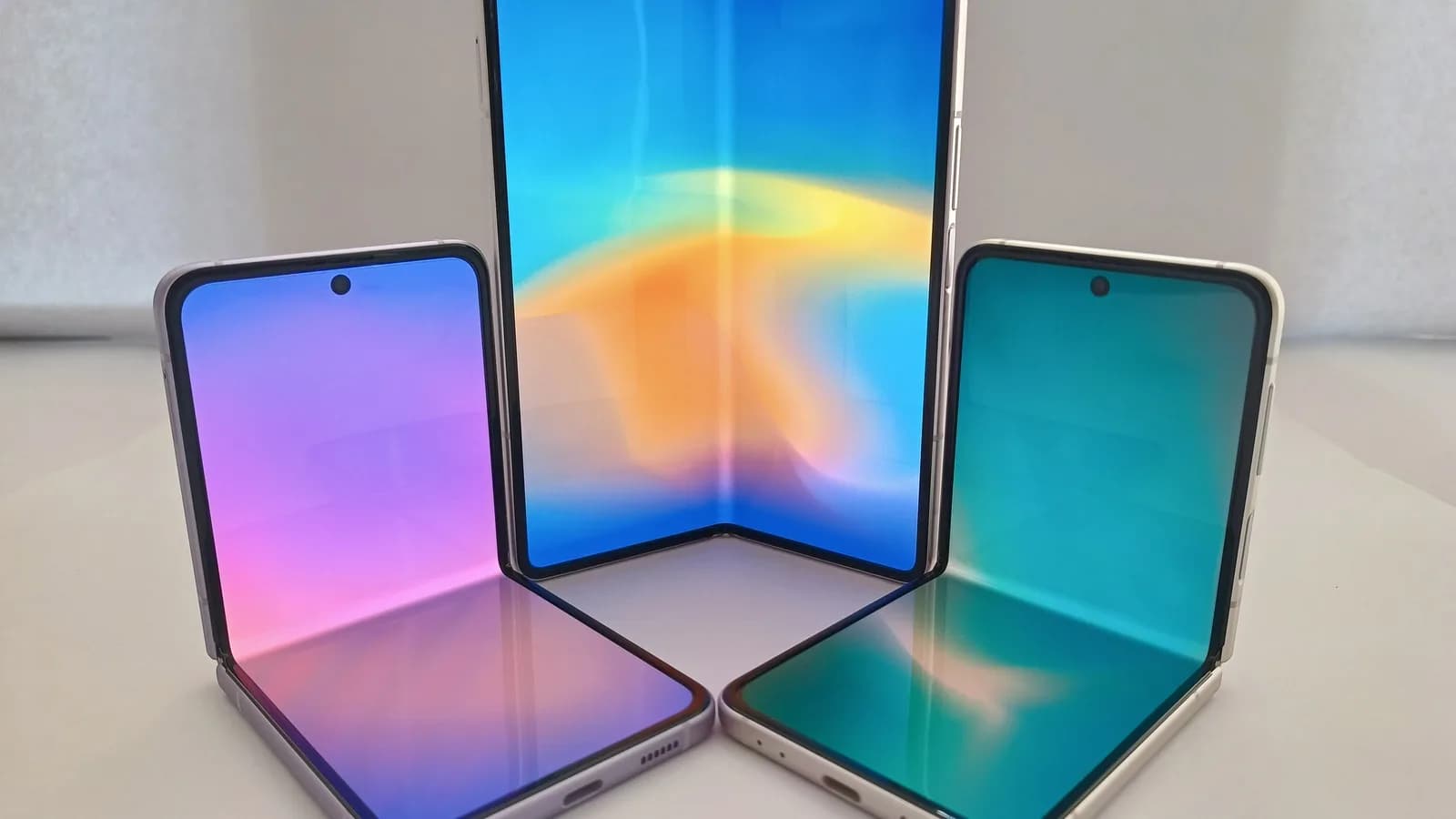 Três smartphones dobráveis genéricos exibidos com as telas internas acesas, imagem ilustrativa sobre a categoria de aparelhos dobráveis