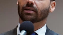 Eduardo Bolsonaro discursa ao microfone em primeiro plano