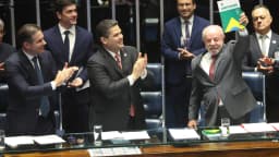 Luiz Inácio Lula da Silva sorri e ergue um exemplar da Constituição em plenário do Congresso