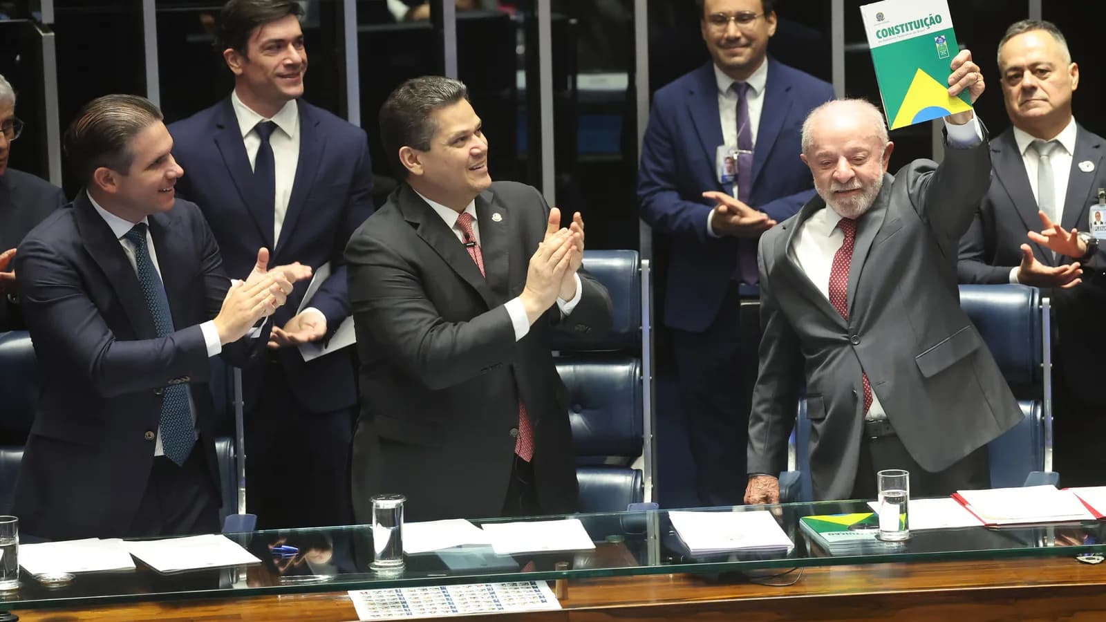 Luiz Inácio Lula da Silva sorri e ergue um exemplar da Constituição em plenário do Congresso